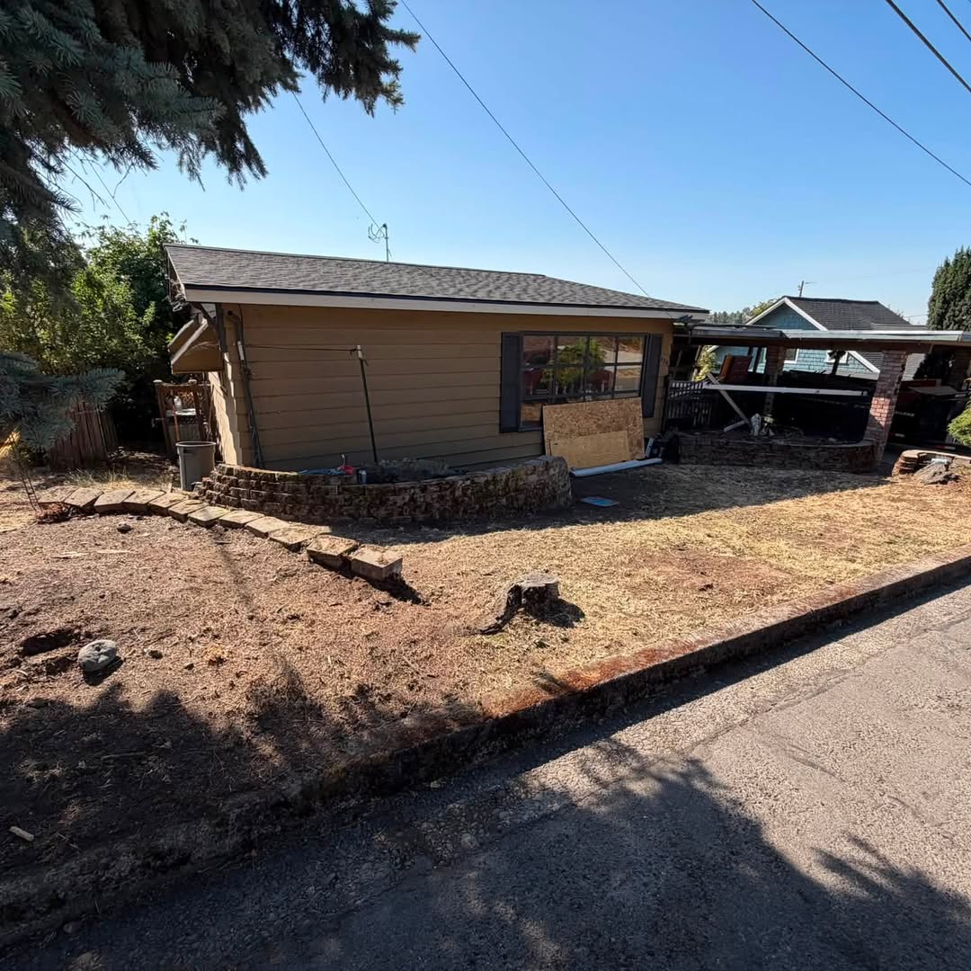 Front yard cleared to dirt and straw beside a tan house